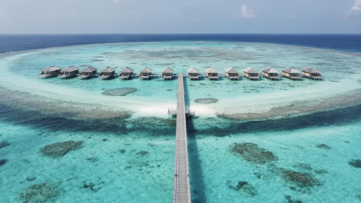 Aerial view of a Maldives atoll jetty and overwater villas at midday